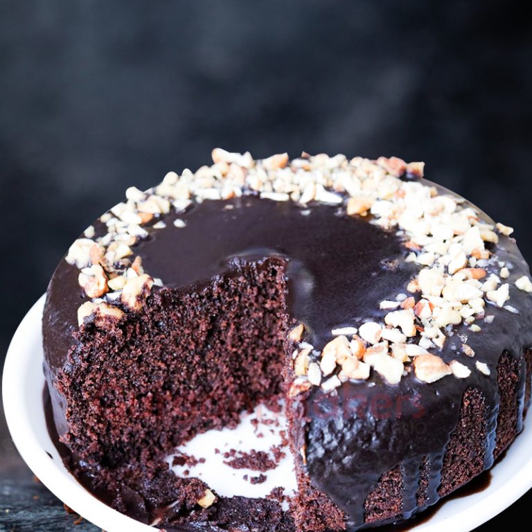 Mouth-watering healthy chocolate cake topped with nuts and a rich, glossy chocolate ganache.