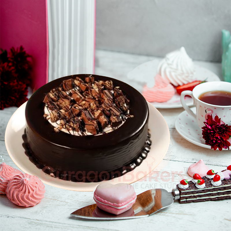 Luscious chocolate birthday cake with crunchy brownie pieces and chocolate glaze on a white plate.