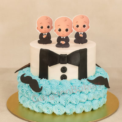 A beautiful two-tiered Baby Boss designer cake with baby figurines
