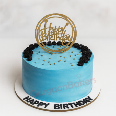 A beautifully decorated bright blue birthday cake with 'Happy Birthday' topper