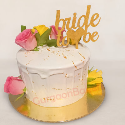 Elegant bride-to-be cake decorated with flowers and a gold topper