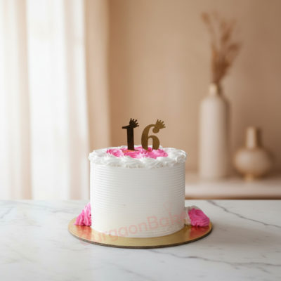A beautifully designed 16-year birthday cake with pink icing and gold number 16
