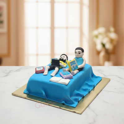 Custom cake depicting two figurines on a bed, working from home