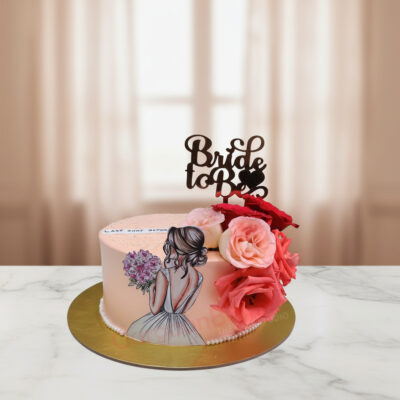 Beautiful bride to be cake adorned with flowers and a cake topper.