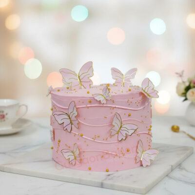 Delicate butterfly cake with pink frosting and gold accents.