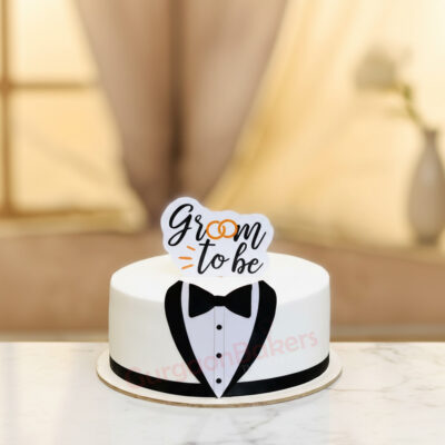 A groom-to-be cake featuring a tuxedo design and a playful topper