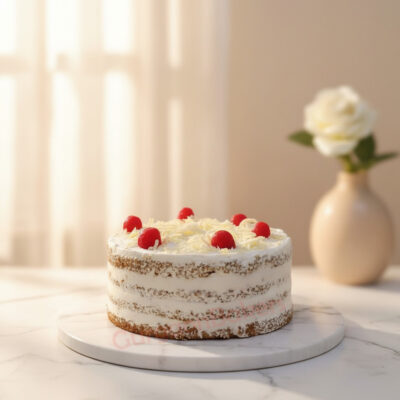 A light cake topped with cherries and coconut flakes on a marble plate