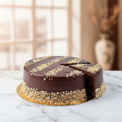 A rich chocolate cake topped with nuts and a glossy ganache