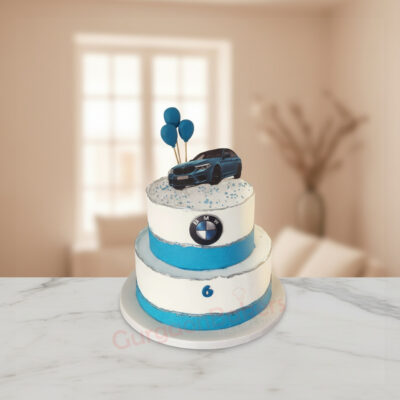 BMW themed cake with blue and white design, featuring balloons and a car topper.