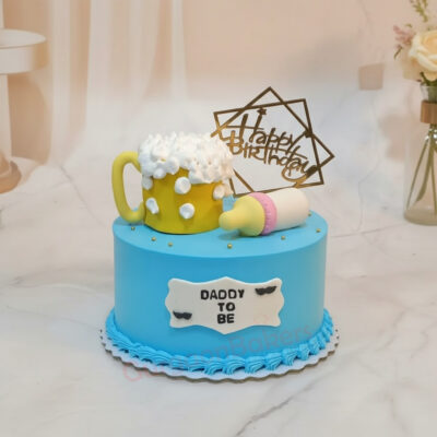A colorful Daddy To Be themed cake with a beer mug and baby bottle decorations.