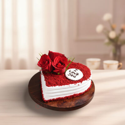 A beautifully decorated heart-shaped red velvet cake with roses and an 'I love you' message on top.