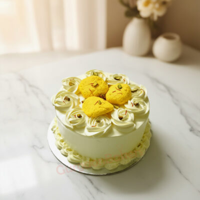 A beautiful rasmalai cake with cream roses and yellow rasmalai toppings