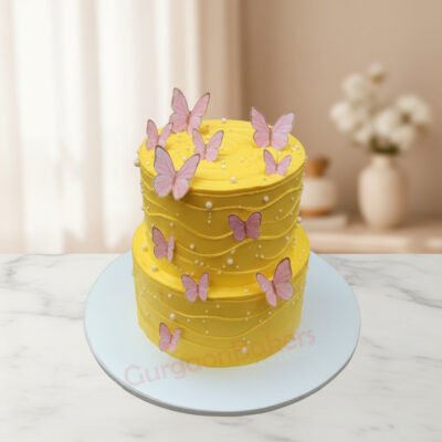Two-tier mango birthday cake decorated with pink butterflies and white pearls in Gurgaon | Gurgaon Bakers